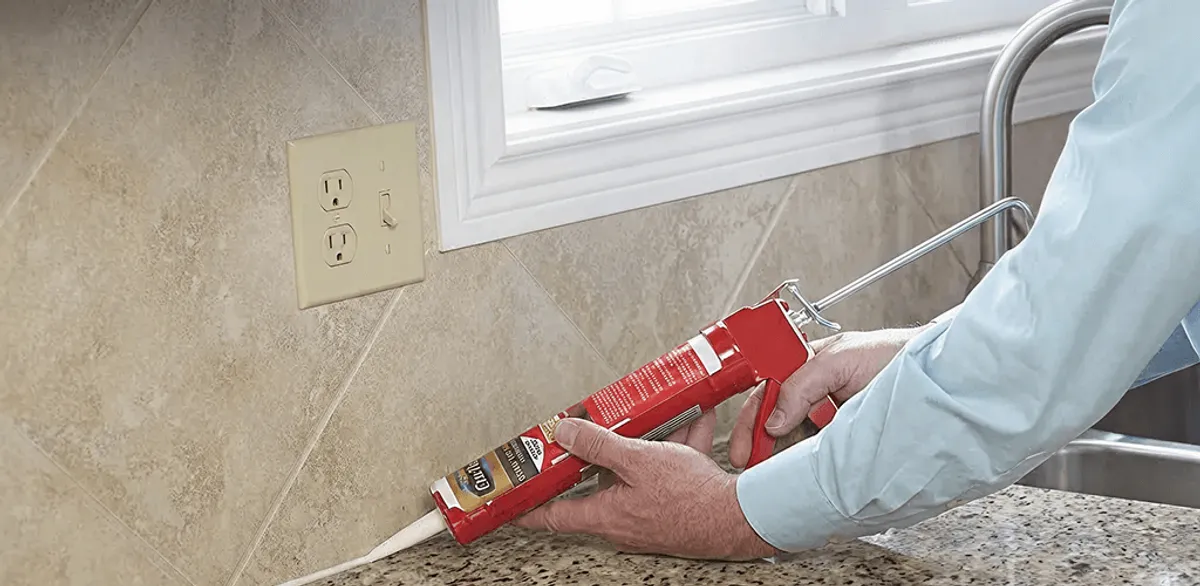 Handyman applying caulk along a kitchen backsplash and countertop seam in Indianapolis, IN